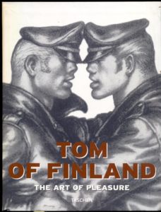 Cover of 'Tom Of Finland: The Art of Pleasure' art book by Taschen featuring two men in motorcycle leathers with faces close together as though they're about to kiss.